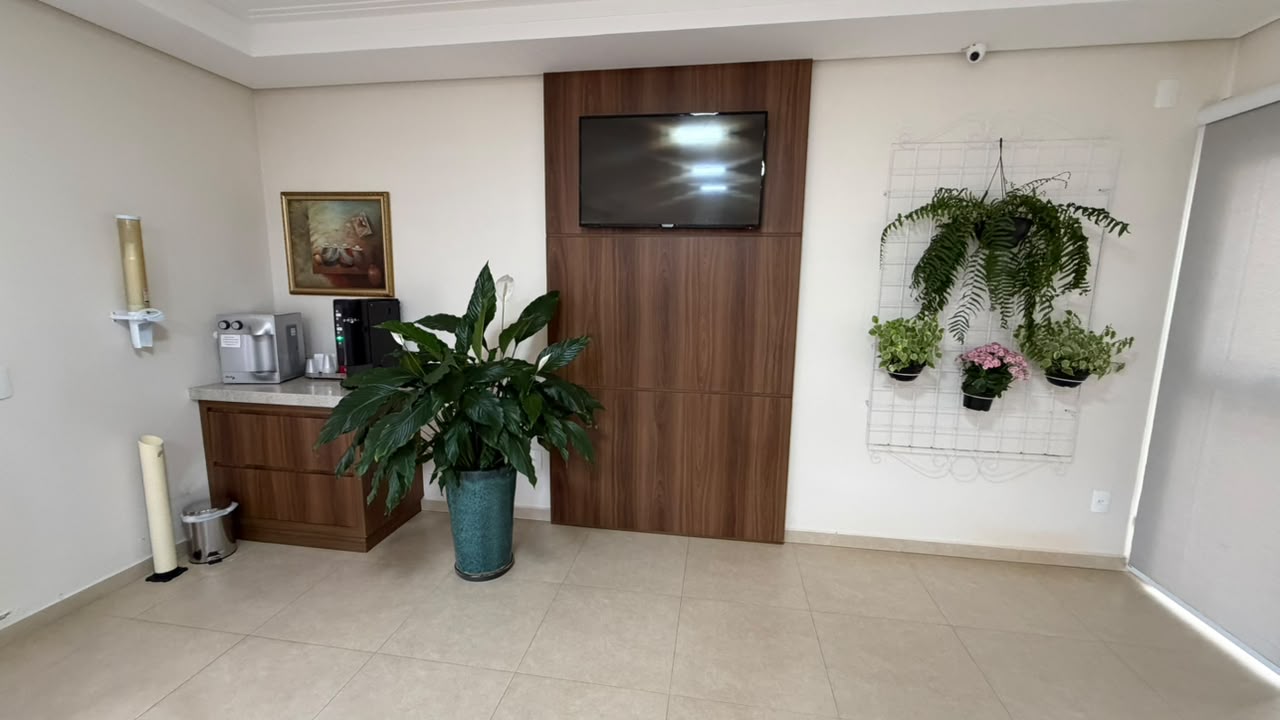 Canto do café da Clínica Revita com plantas e televisão